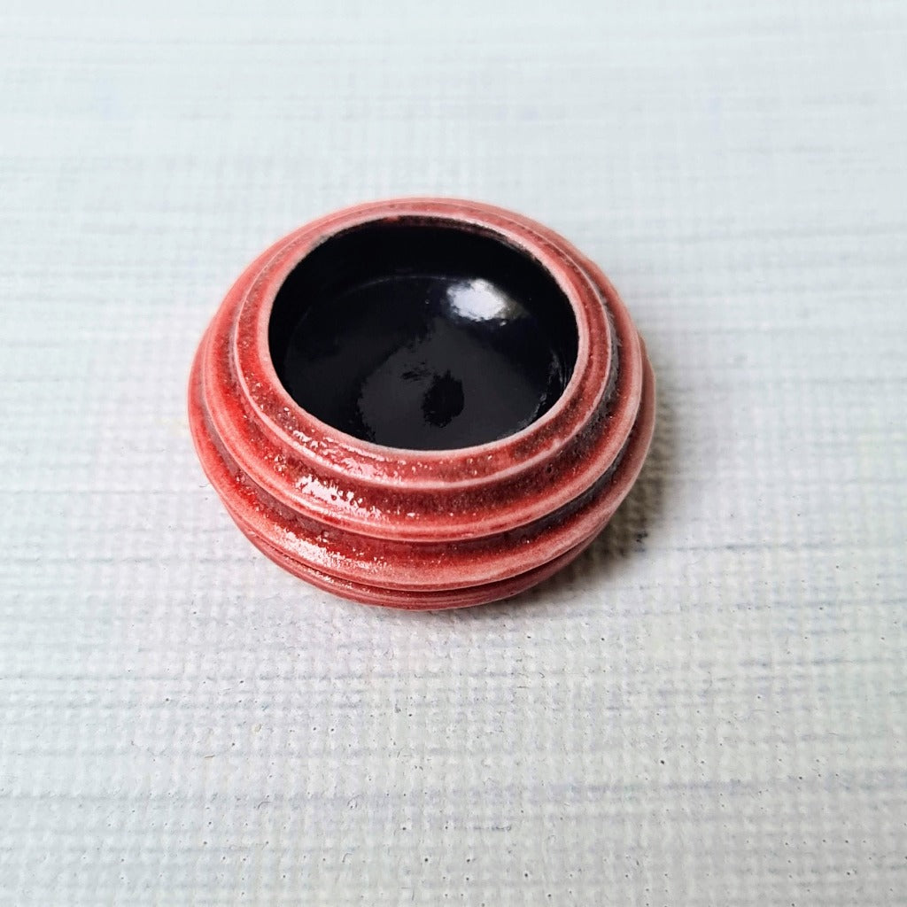 Rood minipotje met zwarte binnenkant. porselein